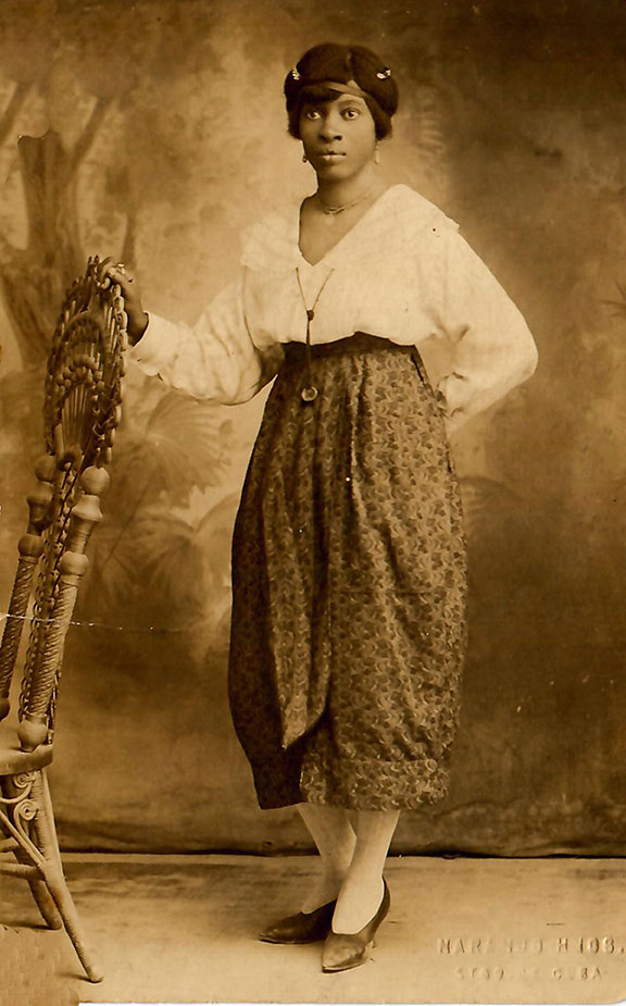 sepia-toned image of woman wearing white blouse anf flowing trousers