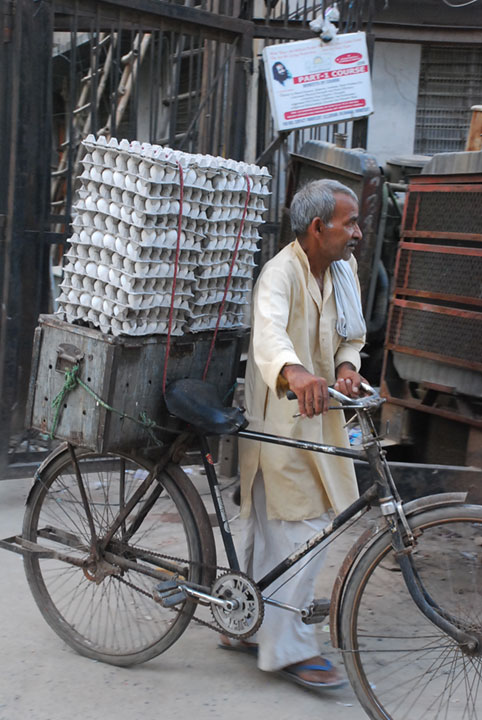 man with egg cartons balanced on his bike