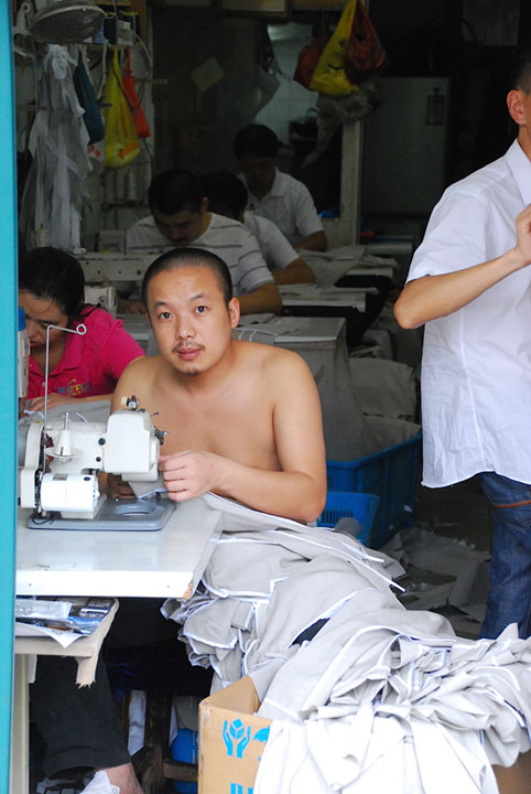 man in sweatshop at sewing machine