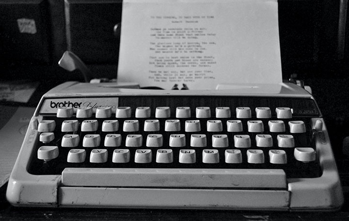 black and white image of typewriter with page of poetry