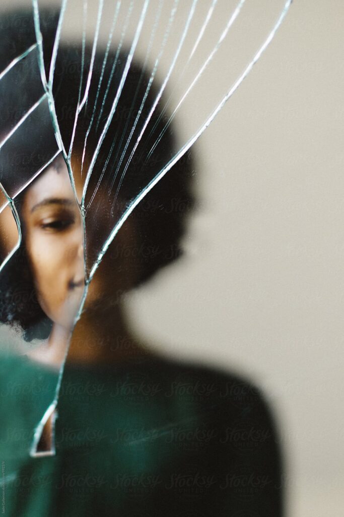 Cracked mirror with warped image of Black woman