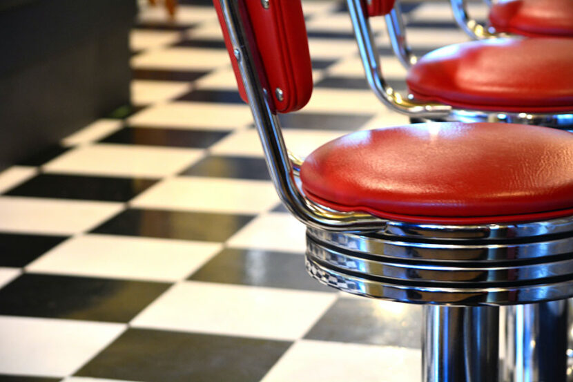 Red seats at a diner counter with checkerboard flooring in the background