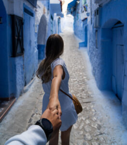 Woman walking down blue corridor leading someone by the hand