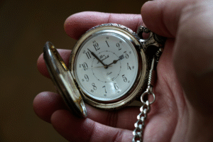 Open pock watch held in palm of hand.