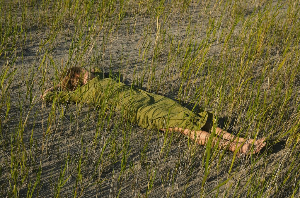 Woman in green dress reclining on beach grass