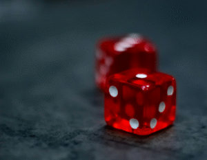 A pair of red and white dice on a dark surface.