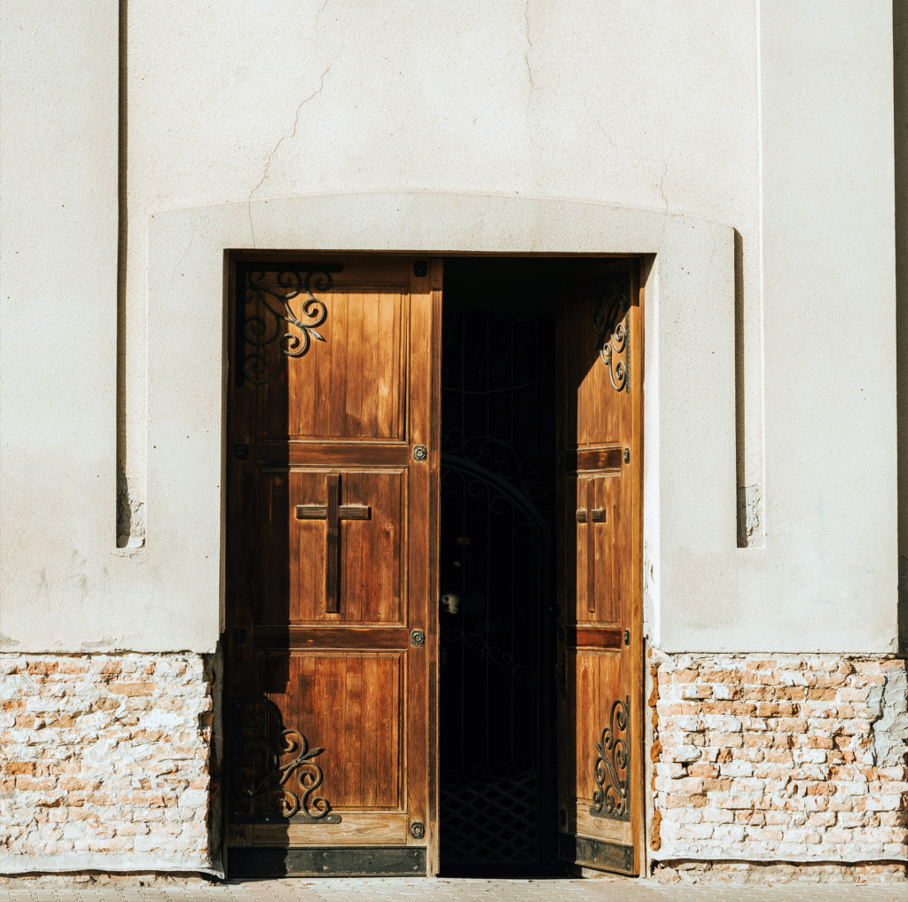 Tall wooden double doors open to a simple sanctuary