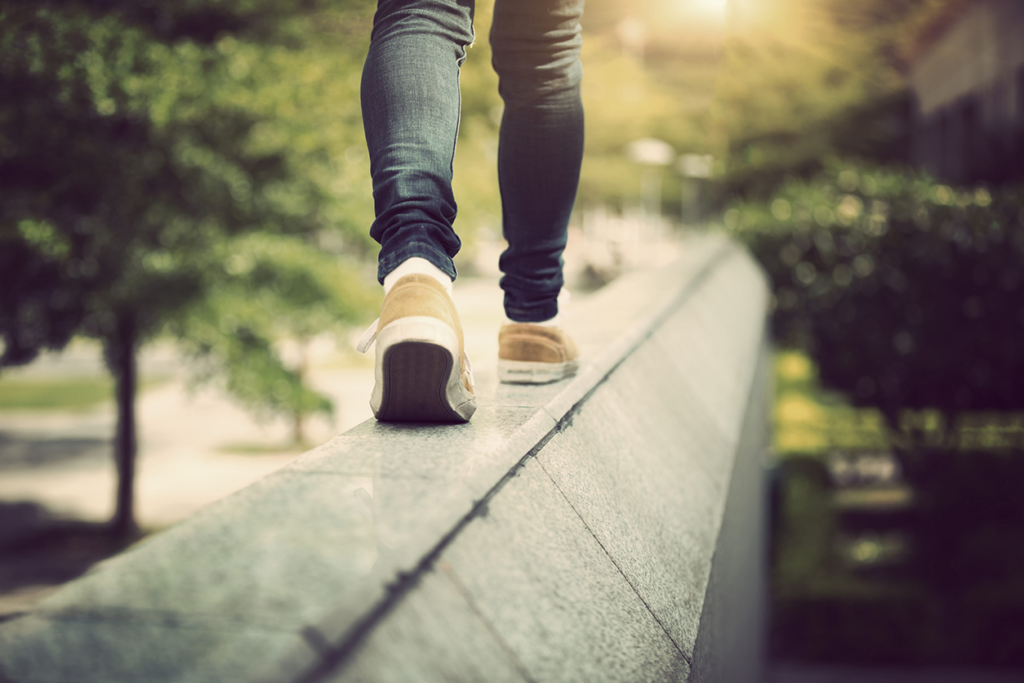 Photo of a teenager’s feet in sneakers walking along a bridge railing