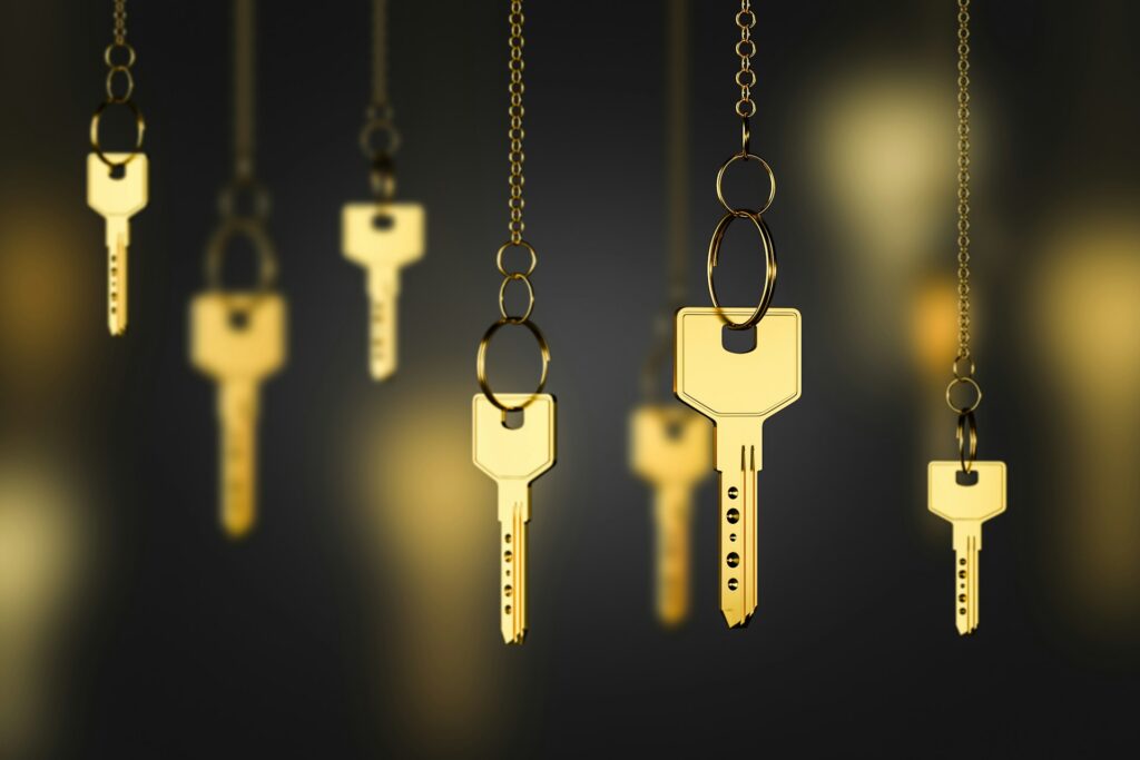 Shiny gold keys dangling on chains against dimly lit, blurred background
