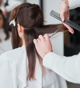Photo of a woman with long hair getting a hair cut at a salon.