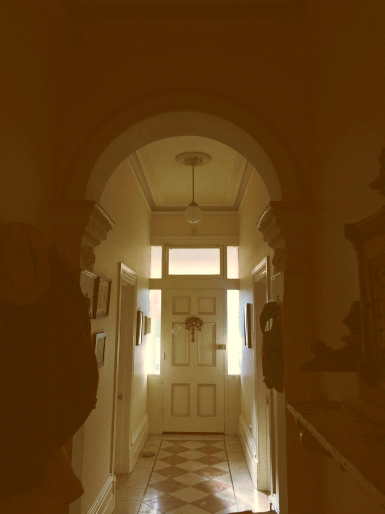 Photo of a hallway in an old house leading to a closed door with a holiday decoration on it.